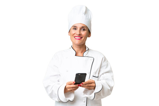 Middle-aged chef woman over isolated background sending a message with the mobile - Powered by Adobe