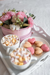Flowers and sweets on white table and balloons on the white bed. Gift for Valentine's day or March 8 or Mother's Day or birthday