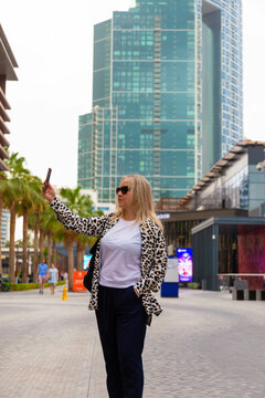 Young woman tourist laughing and taking selfie photo in Dubai Marina in United Arab Emirates. Female traveler and photographer takes picture for her blog.Young happy tourist making selfie