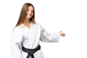 Teenager girl doing karate over isolated chroma key background extending hands to the side for inviting to come