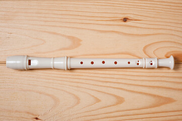 Block flute wind musical instrument photographed on a wooden surface.