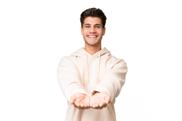 Young caucasian handsome man over isolated background holding copyspace imaginary on the palm to insert an ad