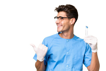 Young dentist man holding tools over isolated background pointing to the side to present a product - Powered by Adobe