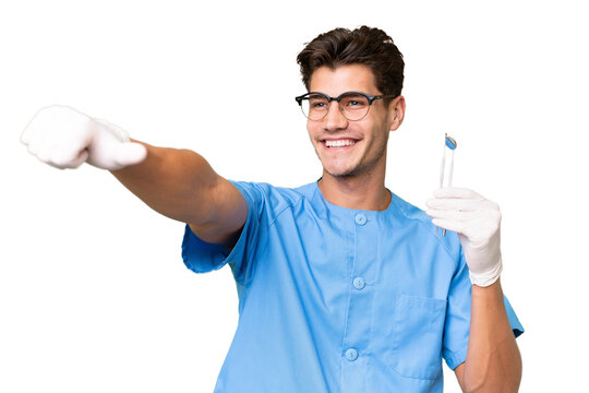 Young dentist man holding tools over isolated background giving a thumbs up gesture