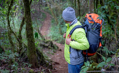 Rear view male walking outdoors with backpack into the wild forest trail