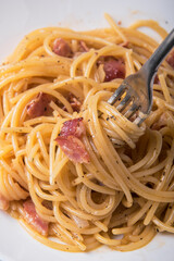 Spaghetti carbonara with parmesan cheese on a marble table.