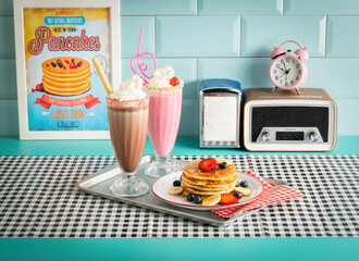 Breakfast of pancakes with fruits, a chocolate milkshake and a strawberry milkshake in vintage...