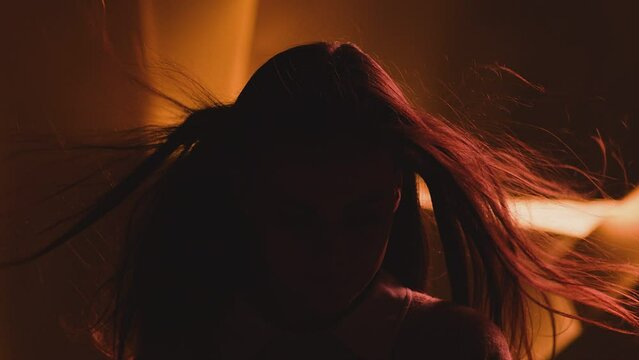 Close up portrait of pretty brunette female model . Beautiful attractive face of young woman . Hair flowing or blowing in wind . Face Changes Depending on the Lighting . Shadow and light movement . 