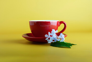 red color tea cup and saucer and leaves, flowers ornaments on yellow background