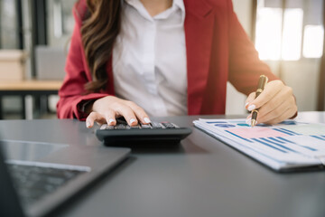 Businesswoman working with tablet and using a calculator to calculate the numbers of static in...