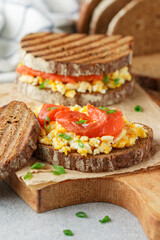 Scrambled eggs and smoked salmon on rye bread with green onions. A sandwich for breakfast. Selective focus - 570847881