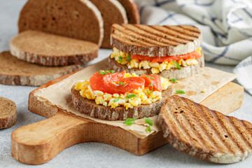 Scrambled eggs and smoked salmon on rye bread with green onions. A sandwich for breakfast. Selective focus - 570847886