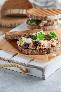 Sandwich with baked fish (tuna or salmon) with black olives, Feta cheese and parsley on rye bread. Mediterranean seafood breakfast.   Selective focus