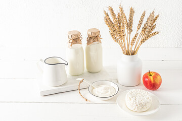 beautiful festive composition for the Jewish holiday of Shavuot. dairy products on a white wooden board and a vase with bread ears. white background.