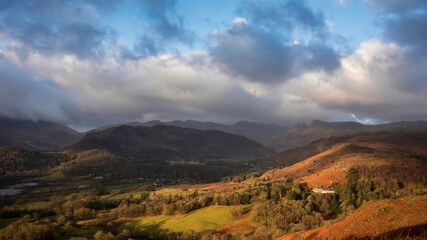 Stunning Winter sunrise golden hour landscape view from Loughrigg Fell across the countryside towards Langdale Pikes in the Lake District