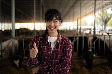 Portrait of a Asian female  farmers who are standing at the cow farm. Confident successful female farmer posing in the cowshed.