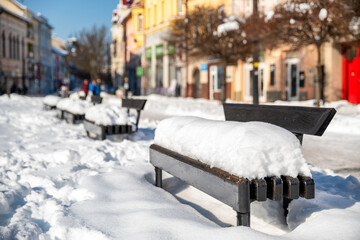 Benches in the town covered with snow in winter. Winter weather in the city