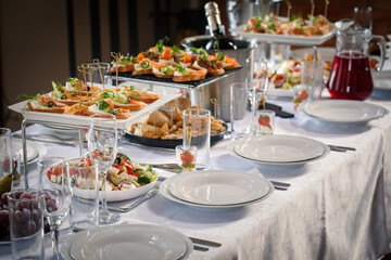 Set table with sandwiches, canapes, salad, wine glasses, plates and a buckets of champagne indoor, selective focus.