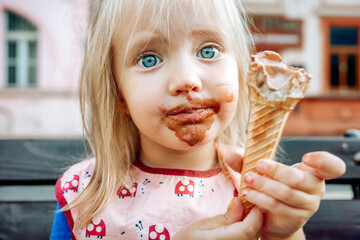 Little dirty faced child girl eating chocolate ice creame