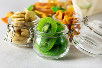 Green Kiwi Banana Persimmon Fruit Preserved in Glass Jars on Gray background