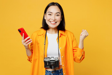 Young woman wear summer clothes hold use mobile cell phone do winer gesture isolated on plain...