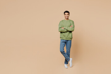 Fototapeta na wymiar Full body smiling fun young man of African American ethnicity wear green sweatshirt hold hands crossed folded isolated on plain pastel light beige background studio portrait. People lifestyle concept.