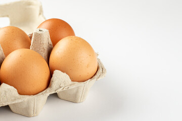 Raw chicken eggs in an egg tray on a white background.