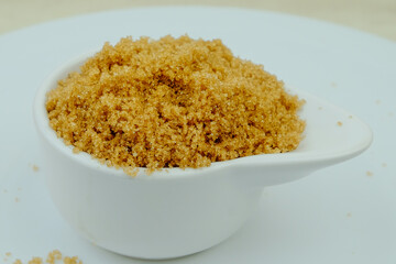 Brown sugar from natural cane juice on a unique white bowl