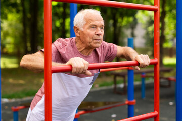 Obraz premium Sportive elderly man training on outdoor sports ground