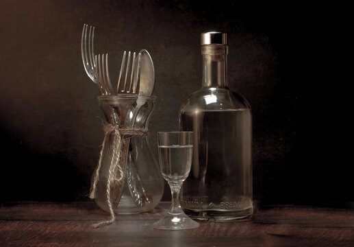 Stylized still life with a bottle of vodka or moonshine with a glass  