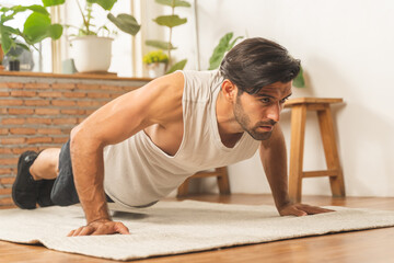 Handsome fitness caucasian young man, guy wearing sportswear training strength muscles workout, exercise training in living room at home for healthy body strong athletic, fit active lifestyle.