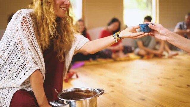 Cacao ceremony, heart opening medicine. Ceremony space. Woman scoops cocoa into a clay bowl.