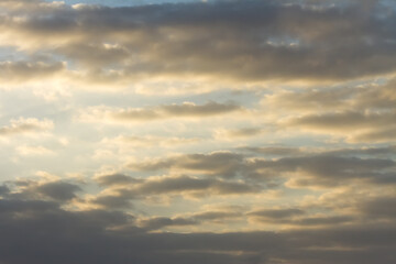 Sky at sunset with gray winter storm clouds. Orange sunbeams sneak through the gaps in some clouds. Bajamar, Tenerife, Canary Islands, Spain.