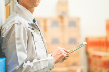 作業服を着て倉庫で在庫管理をする若いビジネスマン