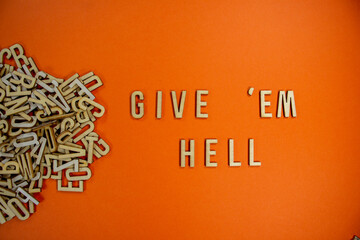 GIVE 'EM HELL in wooden English language capital letters spilling from a pile of letters on a orange background