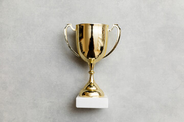 Simply flat lay design winner or champion gold trophy cup on concrete stone grey background....