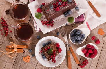 Chocolate sponge cake with fresh fruit on white dish.