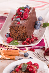 Chocolate sponge cake with fresh fruit on white dish.