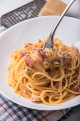 Spaghetti carbonara with parmesan cheese on a marble table.