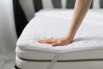 woman check mattress with textile cover in bedroom, closeup