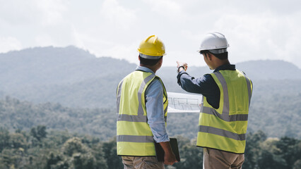 Two young maintenance engineer man working with blueprint on the mountain, Environmental...