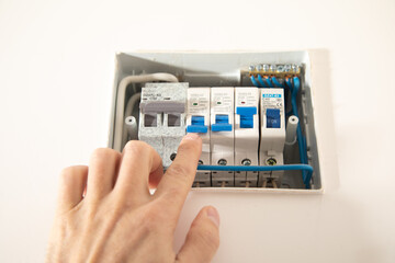 Male hand switching electric board at home.