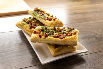 mini slices of puff pastry pizza on a wooden background. Food concept. Bakery.