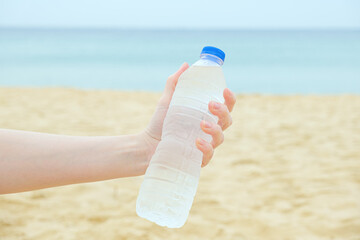Woman holds a plastic bottle with clean drinking water in her hand against the background of a...