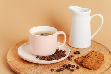 Coffee cup, roasted coffee beans, cookies and jug with milk on a wooden tray. Morning breakfast concept. Closeup