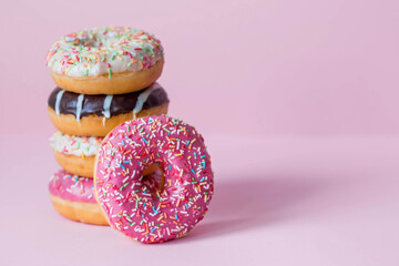 Delicious dessert. Pink, white and chocolate donuts with multicolored sprinkles on a pink background of Sweets. Confectionery products.