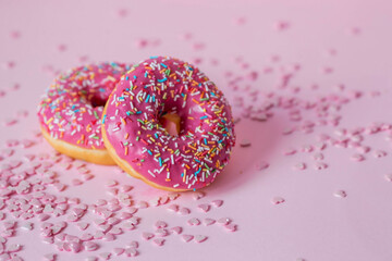 Delicious dessert. Pink donuts with multicolored sprinkles on a pink background of Sweets. Confectionery products.