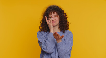 Upset disappointed young curly haired woman wipes tears and cries from despair, being sad because...