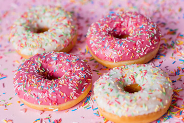Delicious dessert. Pink donuts with multicolored sprinkles on a pink background of Sweets. Confectionery products.