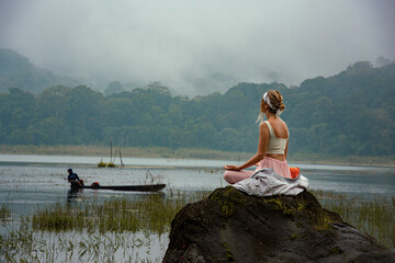 Meditation of a young woman on the shore of a lake in the mountains